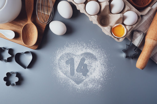 数字14和一颗面粉做成的心。情人节的概念。为情人节做自制饼干，平铺，俯视图。在灰色背景下烘烤的配料图片下载
