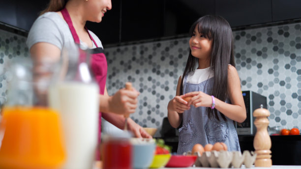妈妈和可爱的小女儿在厨房里一起准备做煎饼。图片下载