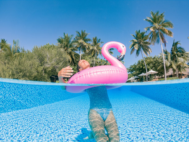 女子在游泳池里玩充气火烈鸟图片下载