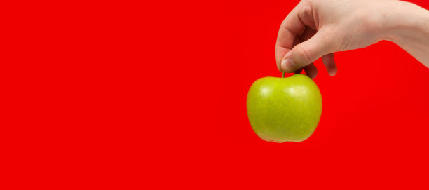 手握美味的有机绿色苹果孤立在红色背景图片下载