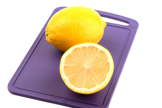 一个柠檬和半个水果放在塑料切菜板上，白色背景。图片下载