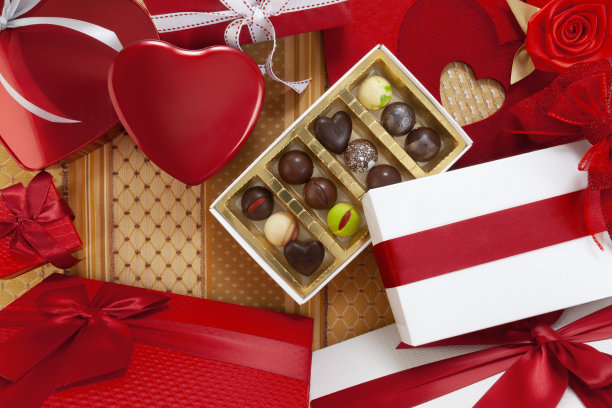 情人节的背景，由巧克力和红色心形金属盒子组成的礼品盒，配有蝴蝶结和丝带，俯视图上用装饰性织物装饰。用于贺卡或糕点海报模板图片下载