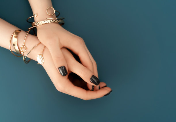 时尚的黑色指甲设计与金色手镯在水背景。奢侈品的概念。节日背景为您的设计。图片下载