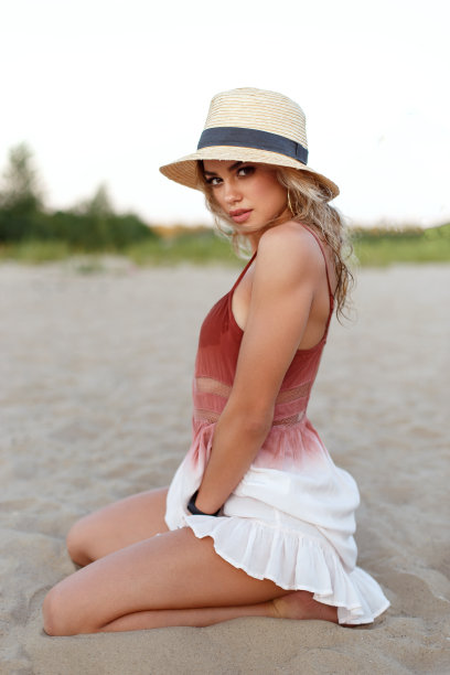 一个美丽的年轻女孩的肖像穿着一件轻盈的衣服在海滩上。图片下载