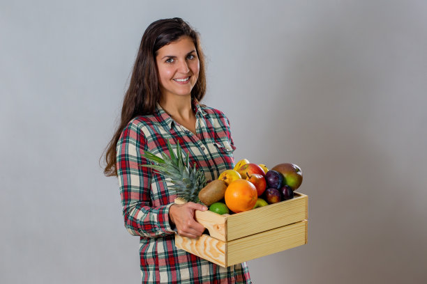 年轻女子拿着装满新鲜水果的木箱图片下载