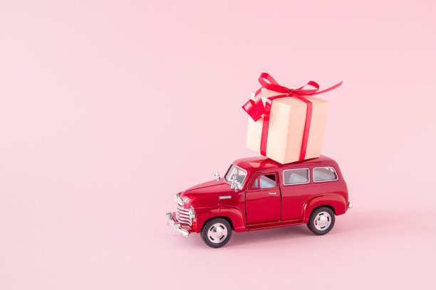 俄罗斯约什卡尔-奥拉- 2020年12月15日:粉色背景上的礼盒复古玩具车。2月14日情人节配送概念。3月8日世界妇女节。图片下载