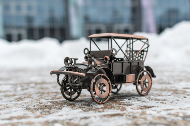 灰色背景下的混凝土路面上停着一辆青铜玩具复古车图片下载