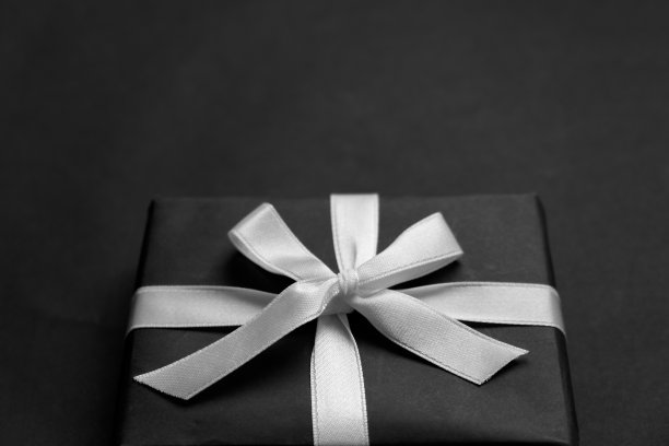 礼品盒，黑色纸包，白色丝带，黑色背景。情人节的概念图片下载