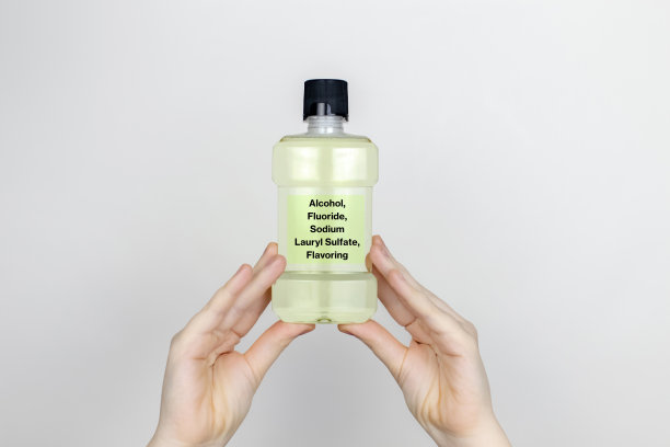 一位妇女正在检查漱口水的有害成分。有害成分。含酒精，氟化物，十二烷基硫酸钠，调味剂的漂洗剂。图片下载