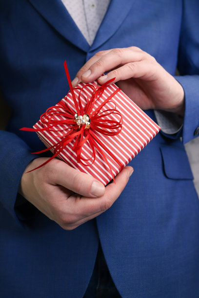 西装男拿着礼盒。图片下载