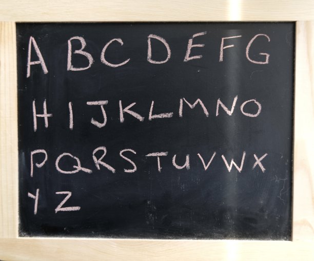 写在黑色黑板上的字母。粉红色的粉笔书写。图片下载