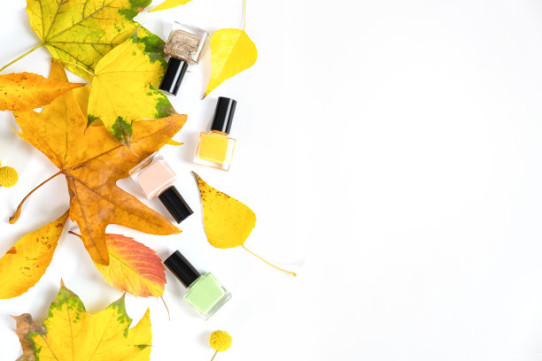 黄色秋叶指甲油瓶子。绿色，玫瑰色，黄色的指甲油瓶子。俯视图拷贝空间图片下载