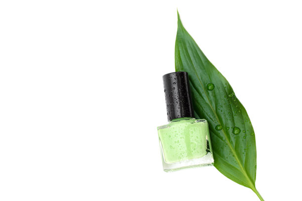 白色背景上的绿色指甲油瓶子。用绿叶装饰的指甲油瓶子图片下载