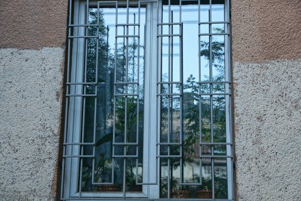 灰色铁栅栏后面有一扇白色的大窗户图片下载