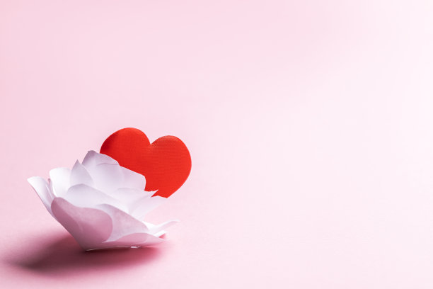 白色纸折纸玫瑰花与红色的心符号在粉色柔和的背景。爱情和浪漫的概念。情人节贺卡概念图片下载
