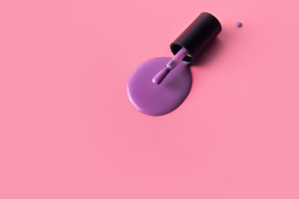 紫色的指甲油刷在粉红色的背景上。紫色指甲油滴。图片下载