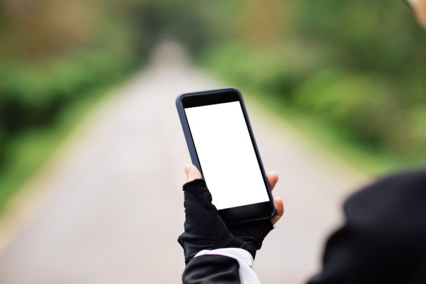 骑山地车的人在森林小径上骑山地车时使用智能手机图片下载