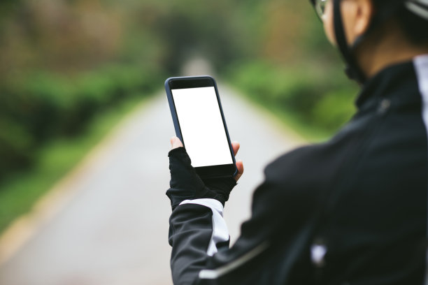 骑山地车的人在森林小径上骑山地车时使用智能手机图片下载