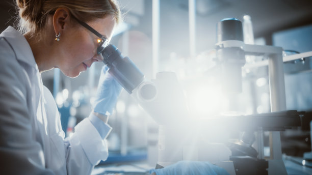 光明医学实验室:美丽的微生物在显微镜下看做测试样品的分析。杰出的科学家，博士，使用高科技设备工作。太阳耀斑的特写。图片下载