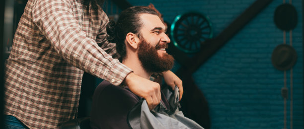在理发店里快乐微笑的大胡子嬉皮士图片下载
