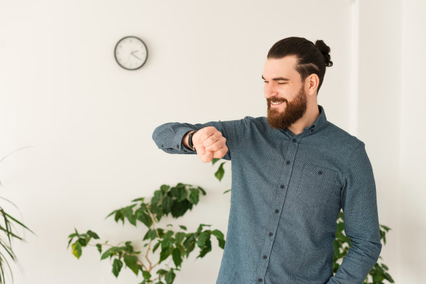 年轻的办公室职员看着智能手表开心的照片图片下载