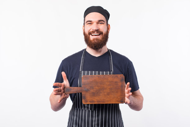 照片中的厨师穿着制服，面带微笑，手里拿着空空的木砧板图片下载