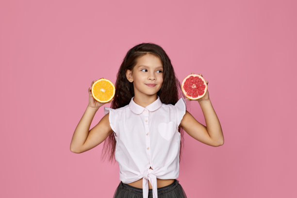 小女孩拿着新鲜多汁的葡萄柚和橙子图片下载