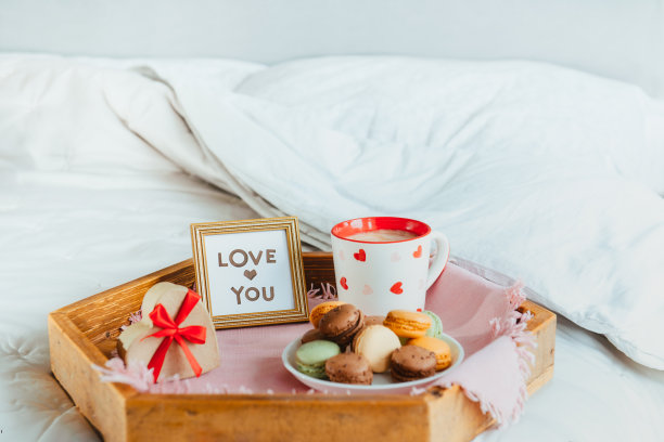 情人节早餐在床上。爱你的卡片在镜框里，一杯咖啡或可可，杏仁饼干，心形礼盒与红丝带在木托盘上。浪漫的早晨。本空间图片下载