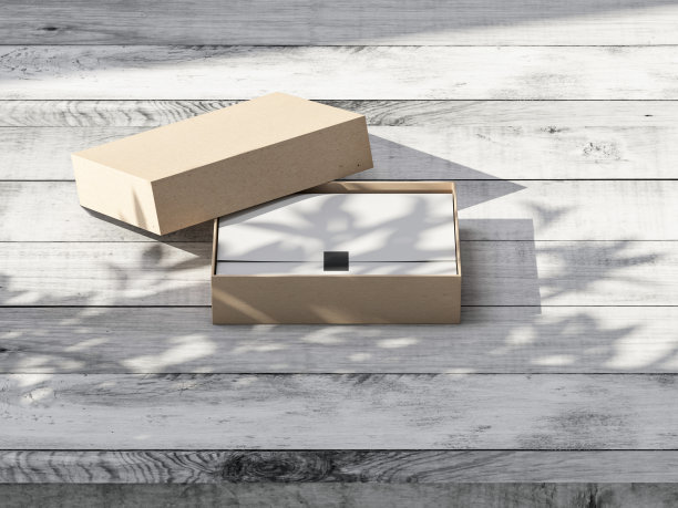 棕色硬纸板礼盒模型与白色包装纸在户外木制桌子上图片下载