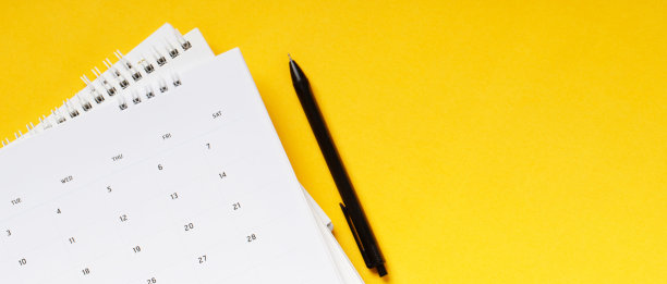 白色干净的日历在纯黄色的背景与拷贝空间，商务会议时间表图片下载