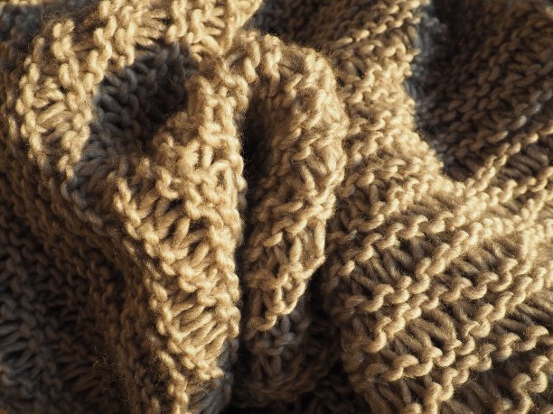 由膨大的聚丙烯酸纱线制成的针织产品，米色或棕色。郁郁葱葱的机框。秋冬季节的保暖衣橱。用前、后和纱针编织图片下载