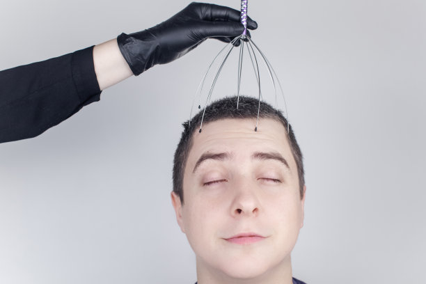 一个男人在沙龙里用毛细管按摩器做头部按摩。客户的脸上流露出放松和喜悦。抗压力按摩的概念和由按摩师提供的服务。图片下载