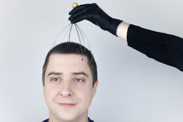 一个男人在沙龙里用毛细管按摩器做头部按摩。客户的脸上流露出放松和喜悦。抗压力按摩的概念和由按摩师提供的服务。图片下载