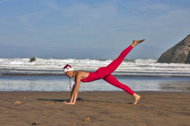女人在红色和圣诞帽使体操在海滩上图片下载