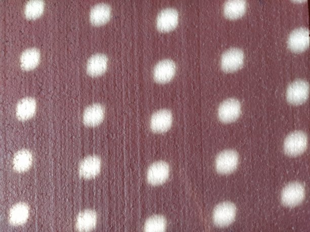 红色背景与圆点。阳光透过百叶窗上的洞照进来，光线在彩色的表面上画出模糊的圆圈图片下载