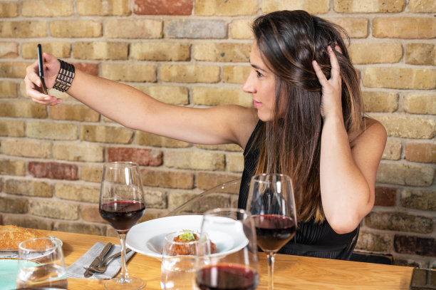 美丽的年轻女子在餐厅用餐时拍了一张自拍照。高质量的照片图片下载