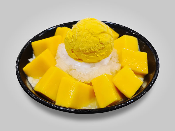 一碗用糯米和芒果块隔开的黄色芒果冰淇淋勺图片下载
