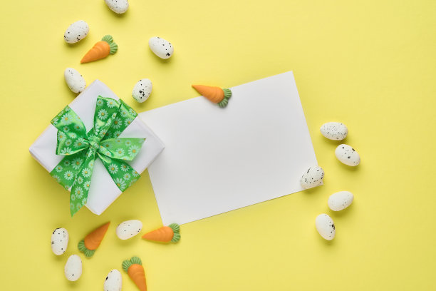 复活节春节贺卡与礼品盒与绿色丝带，鸡蛋和甜胡萝卜在粉红色的背景与地方文字。前视图。图片下载