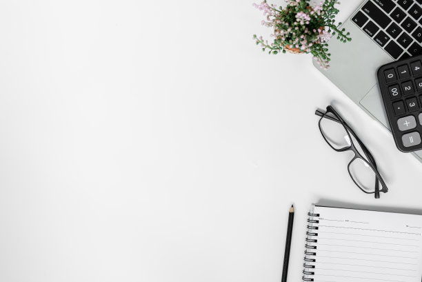 白色的办公桌上。桌上备有空白笔记本、平板电脑、计算器、电脑等办公用品。顶部视图与复制空间。图片下载