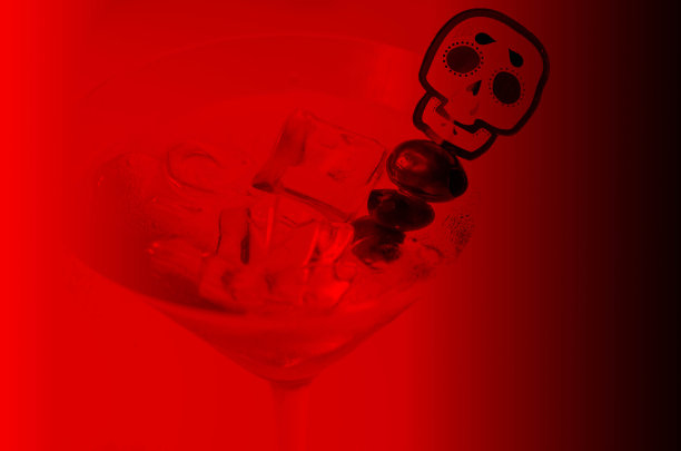 万圣节酒精饮料在马提尼杯与冰块和黑橄榄装饰从墨西哥死亡的Calavera图片下载