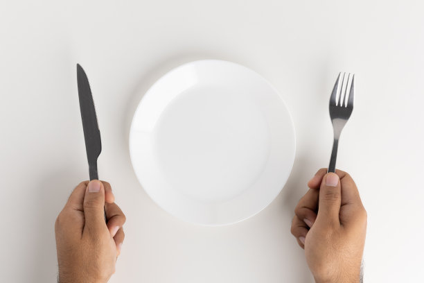 一个男人用刀叉在盘子里吃饭图片下载