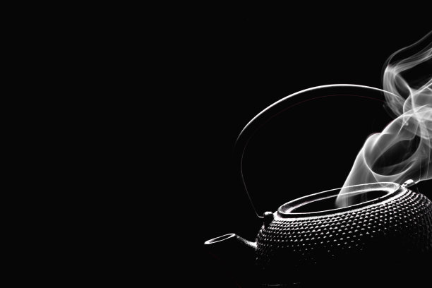 茶壶和沸水。黑色背景上冒着热气的茶壶。烹饪概念。图片下载