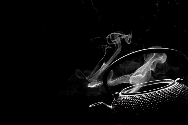 茶壶加沸水。在黑色背景上冒着热气的茶壶。烹饪概念。图片下载