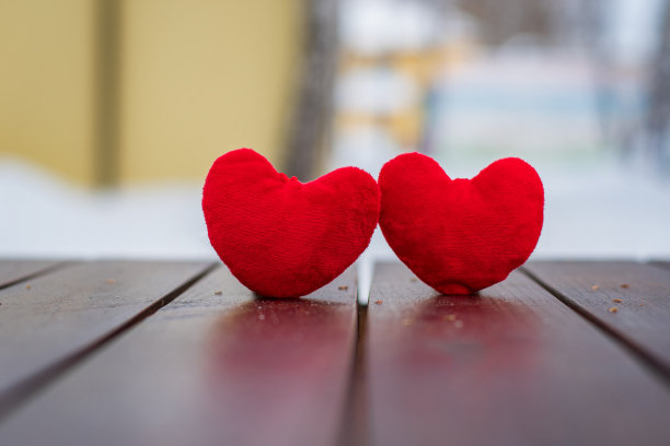 情人节那天，两颗红心站在棕色的木头表面上，背景是抽象的图片下载