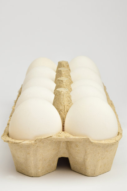 十个白色的鸡蛋在纸板盘里排成两排。托盘倾斜着图片下载