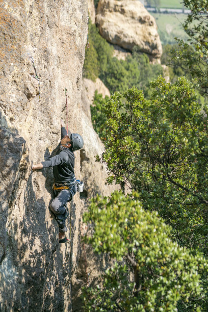 一名登山者在陡峭的悬岩上艰难移动。勇气，力量和许多动机，以成功的挑战和解决困难的移动在岩石上图片下载