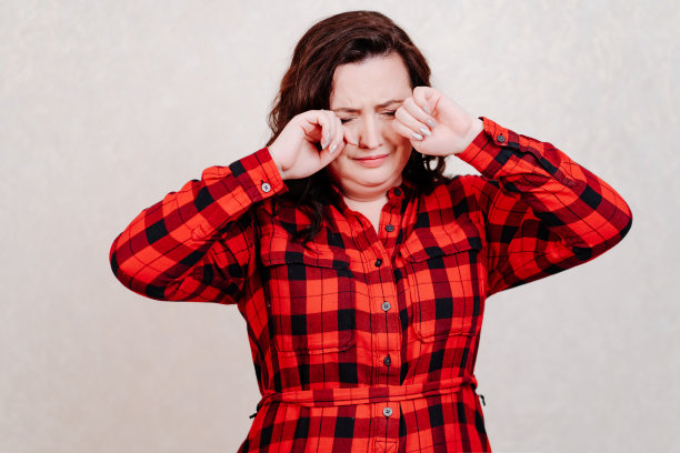 一名身穿红色连衣裙的沮丧女子用手摸着自己的脸图片下载