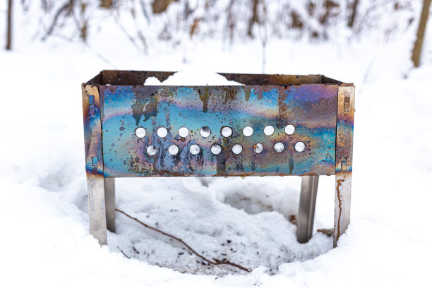 用彩虹金属制成的火盆在冬天的森林里的雪地上，特写。图片下载