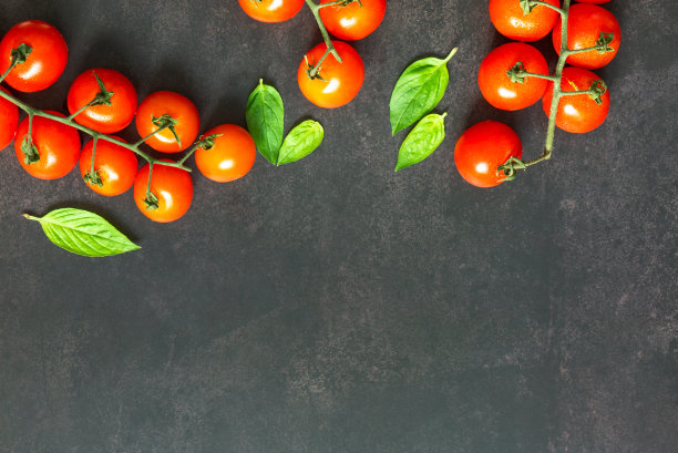 平铺或顶层拍摄各种香料烹饪与藤番茄，罗勒叶的黑色背景与复制空间。图片下载