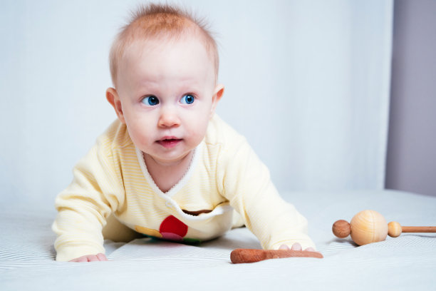 一个可爱的7个月大的蓝眼睛女孩的肖像。一个孩子在明亮的房间里玩木制玩具。由天然材料制成的环保儿童玩具图片下载